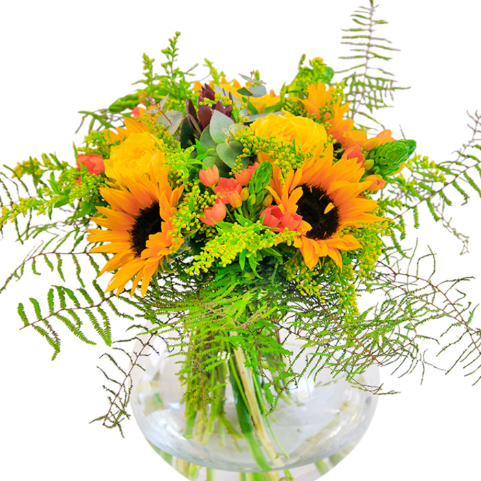 First impressions of this Addington-inspired bouquet are pure exuberance-sunflowers and yellow garden roses, resplendent in their golden glory, appear to capture the very light spilling across local Addington fields. Each sunflower, bold and open-faced, radiates joy from its deep brown center, while clusters of plush, tightly wound roses spiral open beside them, casting delicate shadows. Glossy red Hypericum berries punctuate the lush green foliage, adding a sense of vivacity and gentle contrast, their gleam recalling the vibrance of Addington's seasonal markets. Springs of feathery ferns and cool eucalyptus leaves arch outward, softening the bouquet's silhouette and bringing airiness reminiscent of the breeze through local parks. The clear, globe-shaped vase cradles this abundance, showcasing verdant stems through clear water and creating a sense of transparency and freshness. As sunlight touches each petal, the bouquet glows softly, evoking both comfort and celebration. The arrangement's fragrance mingles sweet floral notes with hints of green, conjuring the serenity of a quiet morning along Addington's leafy lanes. Crafted as the perfect centerpiece for milestone occasions or spontaneous acts of affection, this composition from Florist Addington is a tribute to community, nature, and happiness made tangible.